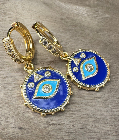 Pair of blue and gold earrings on a wooden surface